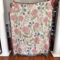 Floral patterned blanket with pink flowers and bees held up against a neutral background