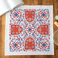 Decorative tea towel with red and blue pattern on a wooden surface