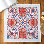 Decorative tea towel with red and blue pattern on a wooden surface