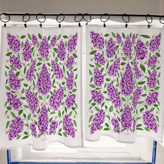 Two white towels with purple floral pattern hanging on a rack.
