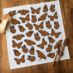 Butterfly-patterned towel on a wooden surface with bread and wooden spoons.