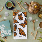 Butterfly-themed towel on a table with tea-making items and a book.