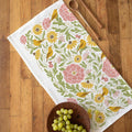 Decorative tablecloth with floral and bird pattern on a wooden surface