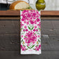 Floral towel with pink flowers and green leaves on a wooden surface
