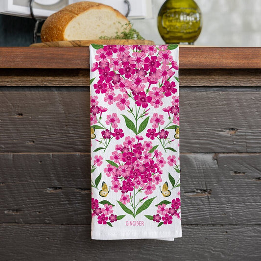 Floral towel with pink flowers and green leaves on a wooden surface