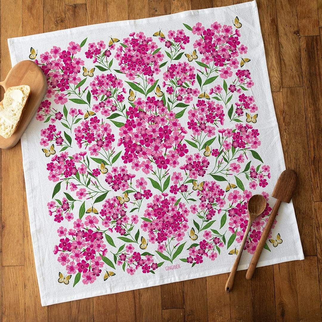 Floral patterned towel on a wooden surface with wooden spoons and bread.