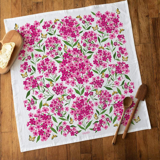 Floral patterned towel on a wooden surface with wooden spoons and bread.
