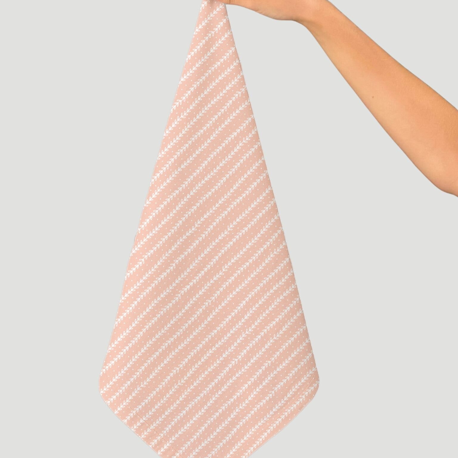Person holding a pink and white striped towel against a light gray background