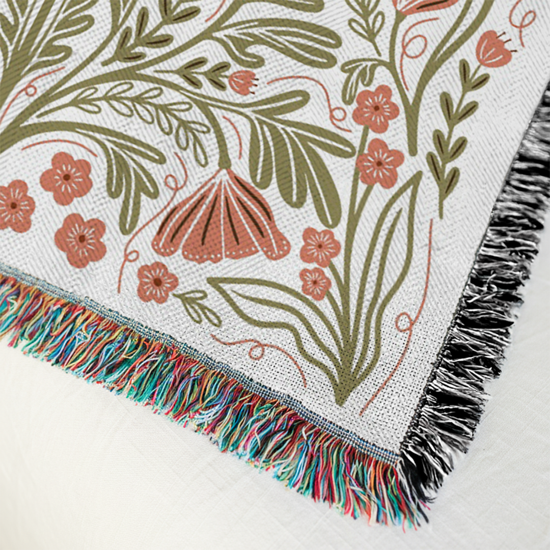 Floral patterned blanket with colorful fringe on a white background