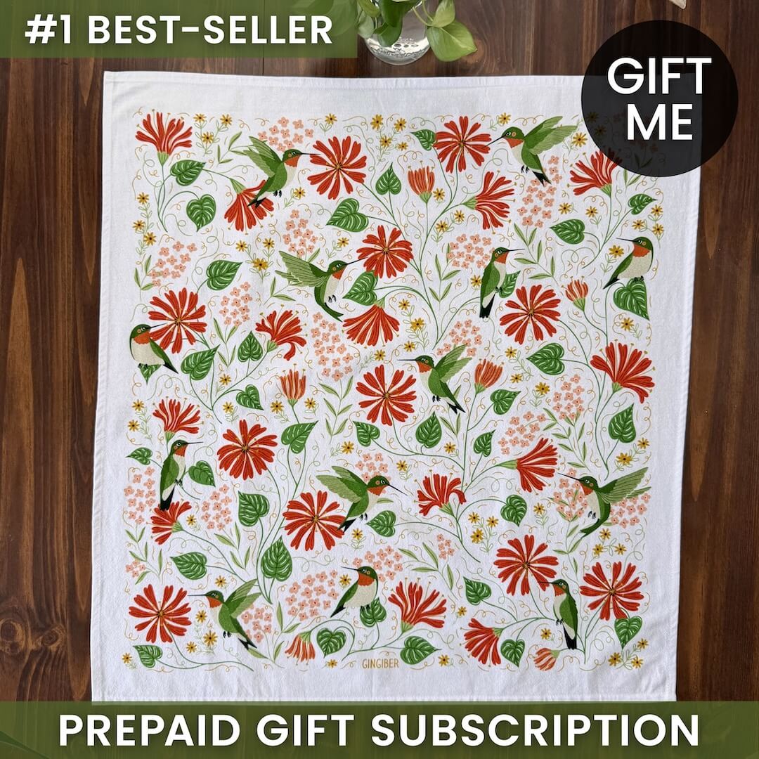 Floral and bird patterned towel with 'Gift Me' and '#1 Best-Seller' text on a wooden surface.