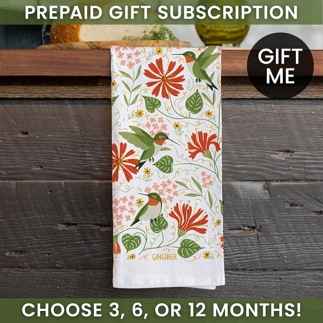 Floral towel with hummingbird design on a wooden surface, promotional text for prepaid gift subscription.