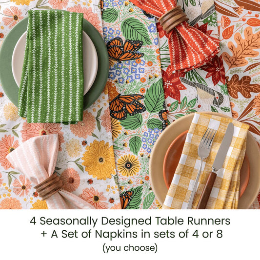 Table setting with seasonally designed table runners and napkins on a colorful tablecloth.