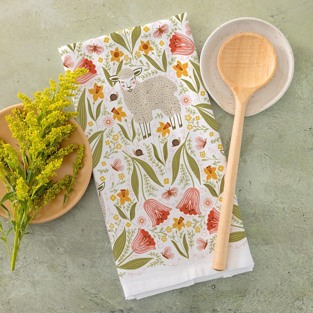 Floral and animal patterned towel with a wooden spoon and bowl on a green surface