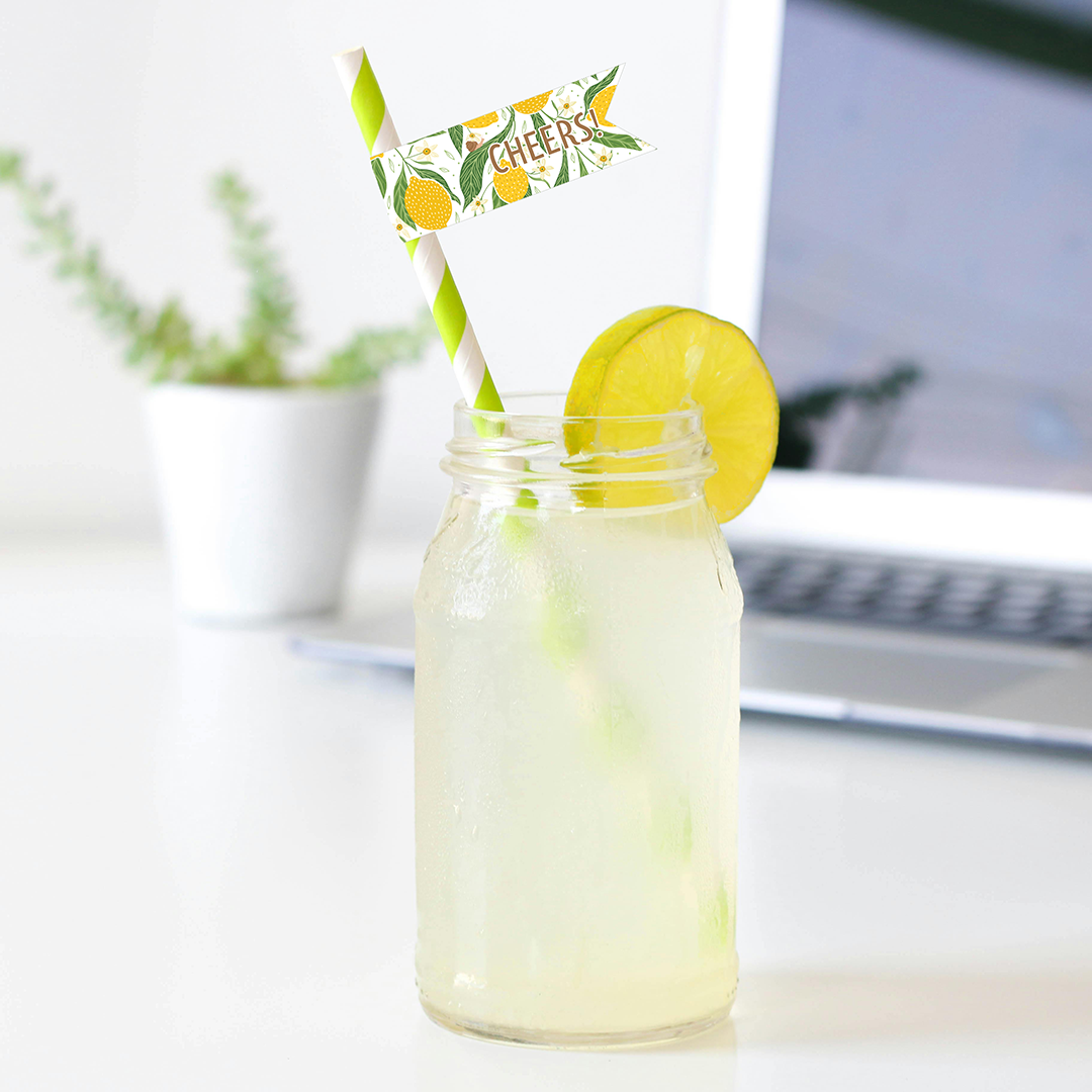 Mason jar with lemonade, lemon slice, and straw on a desk with a laptop in the background