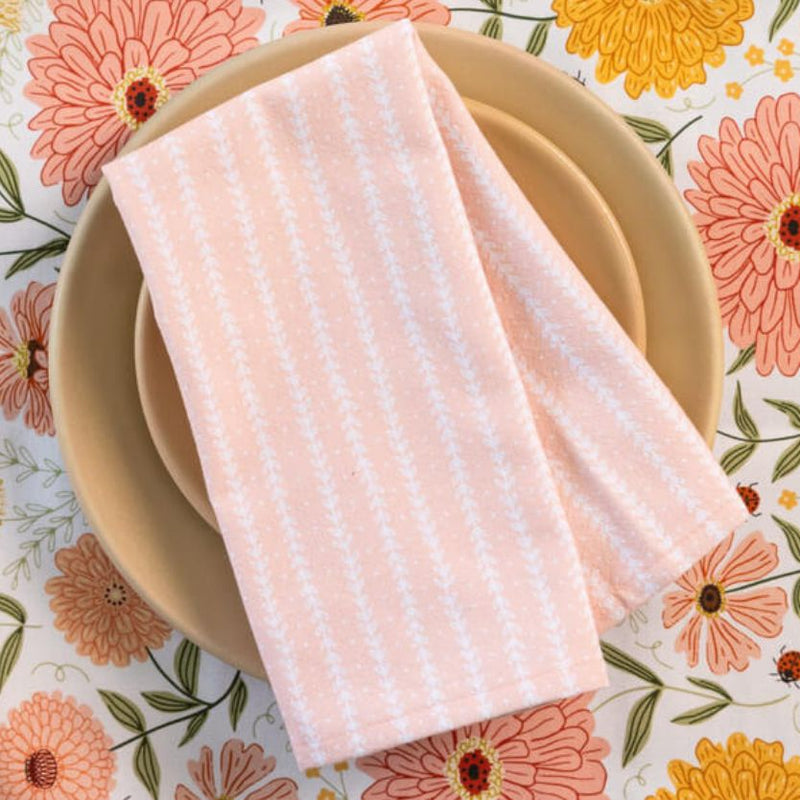 Pink striped napkin on a beige plate with a floral tablecloth