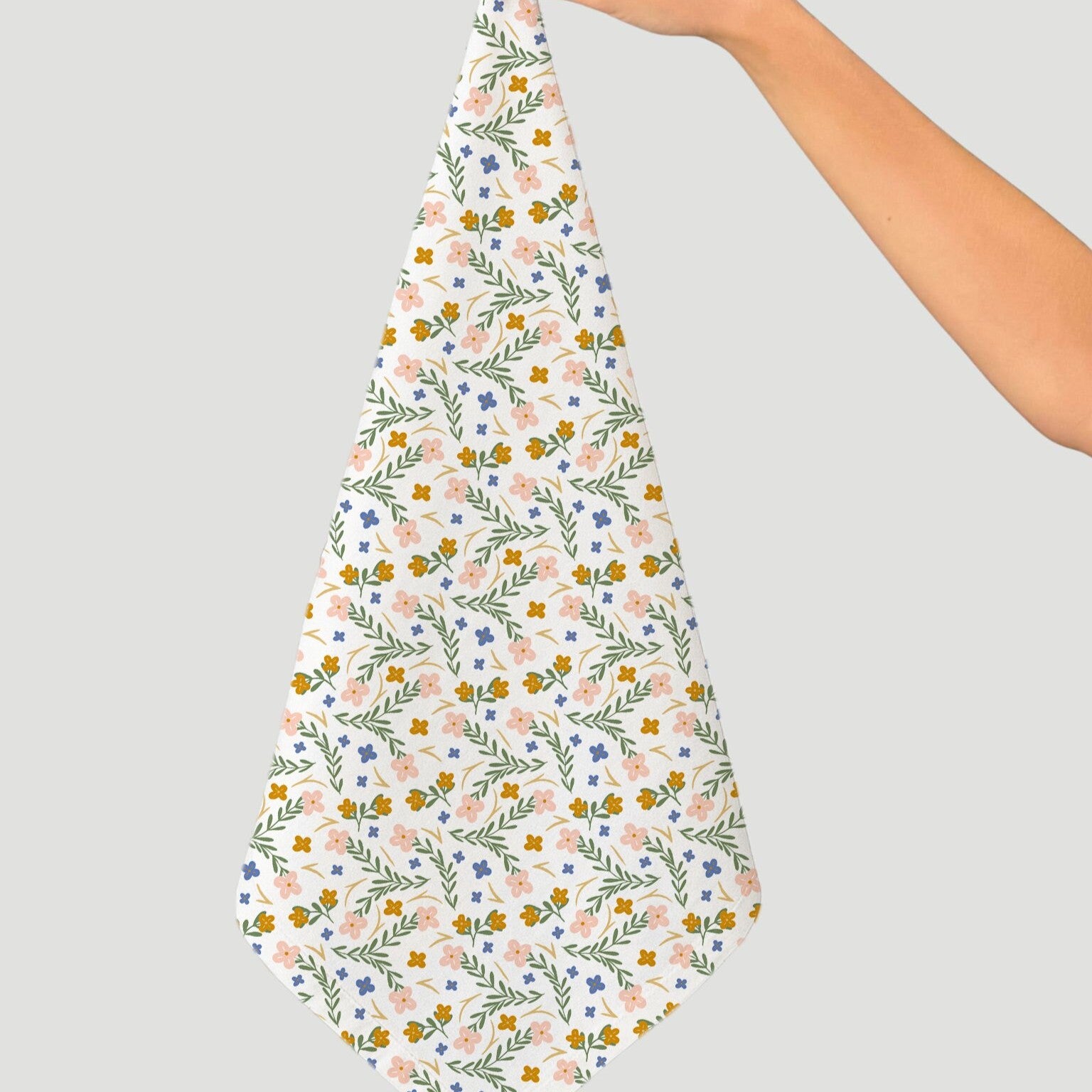 Floral patterned fabric held by a person on a gray background