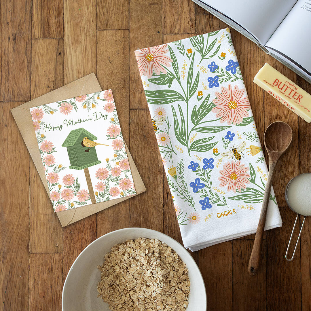 Floral-themed kitchen towel with a card and bowl of oats on a wooden surface