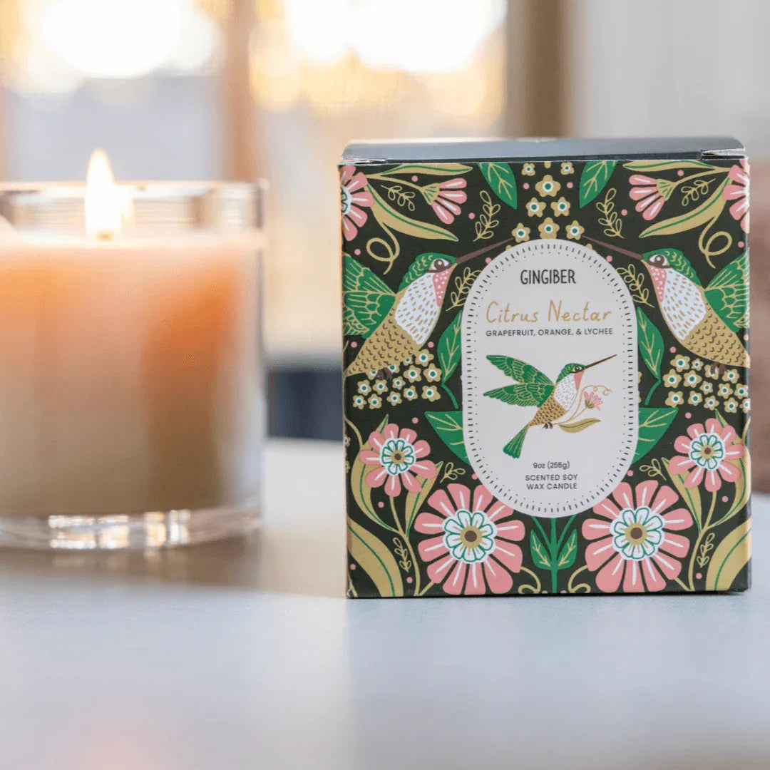 Glass cream-colored candle with green box and hummingbird illustration