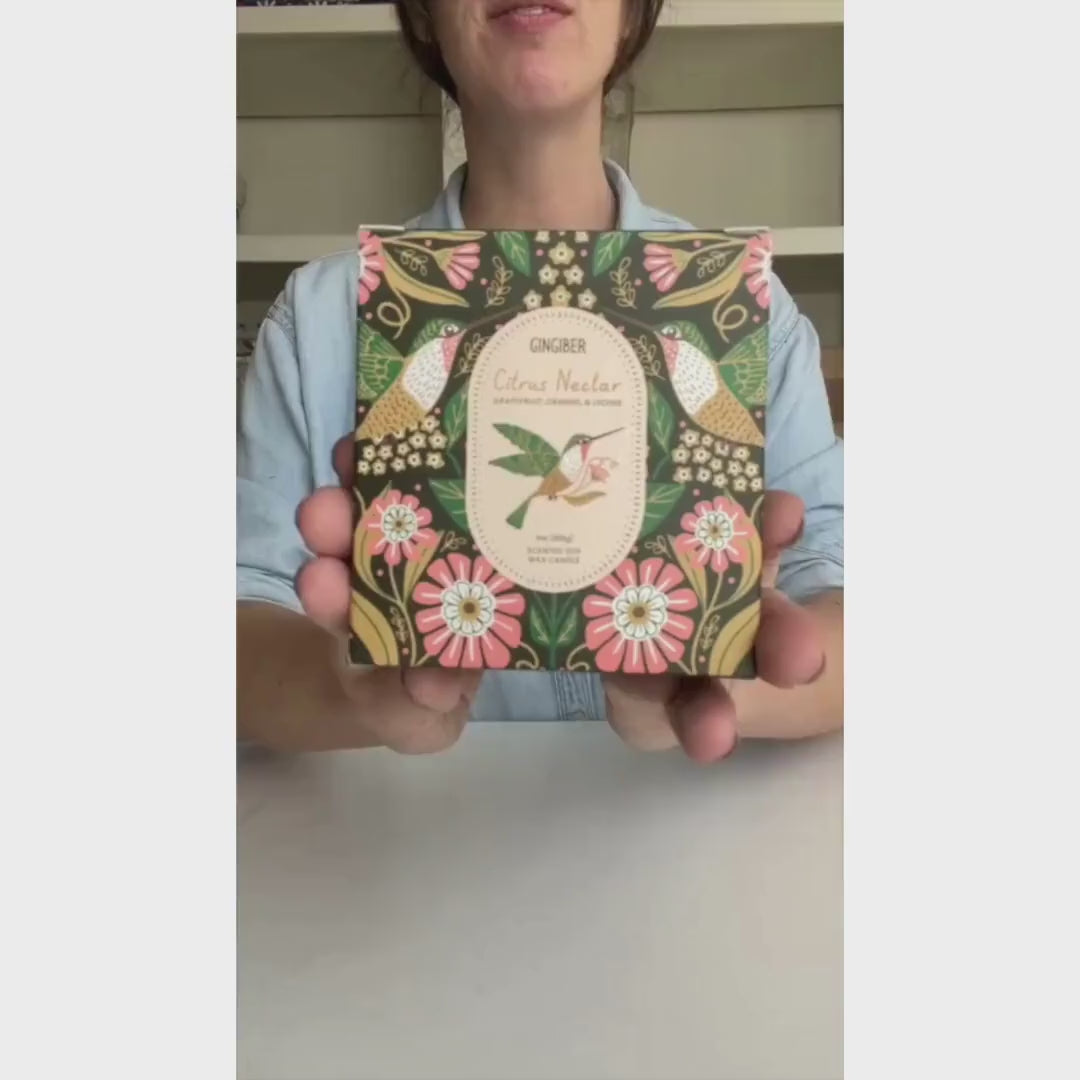 Glass cream-colored candle with green box and hummingbird illustration