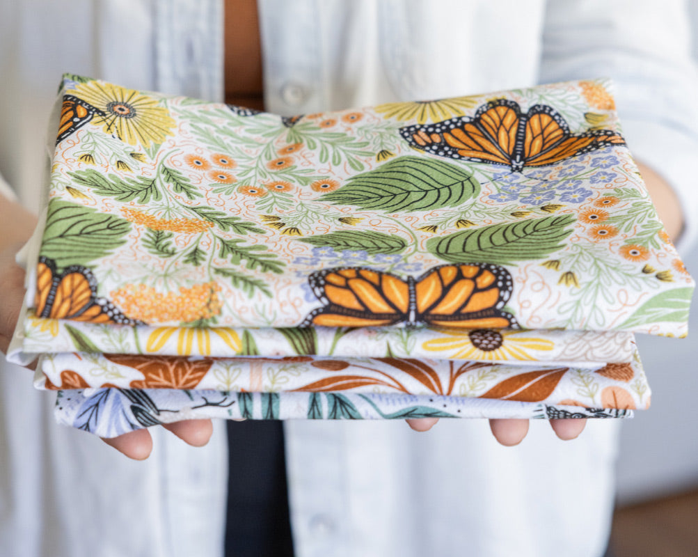 Folded fabric with butterfly pattern held by a person wearing a white shirt.